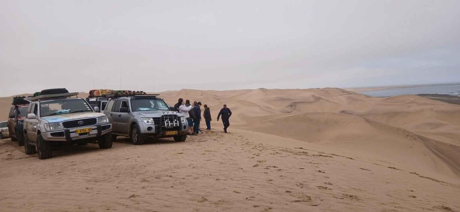 Travellers and vehicles stopped on a dune route