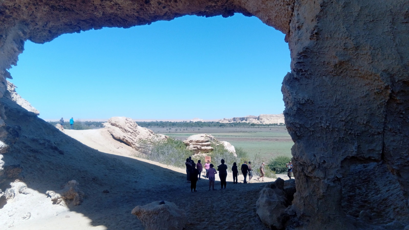 Travellers below a rock arch overlooking the coast