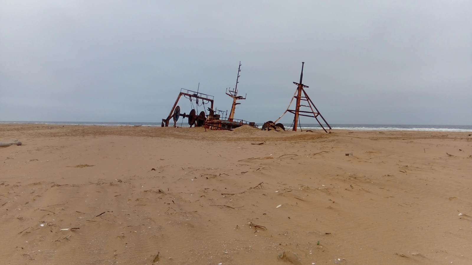 Rusted shipwreck remains on a sandy coast