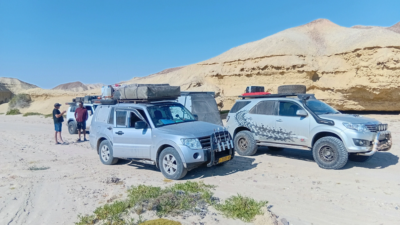 Expedition vehicles and travellers on a sandy route