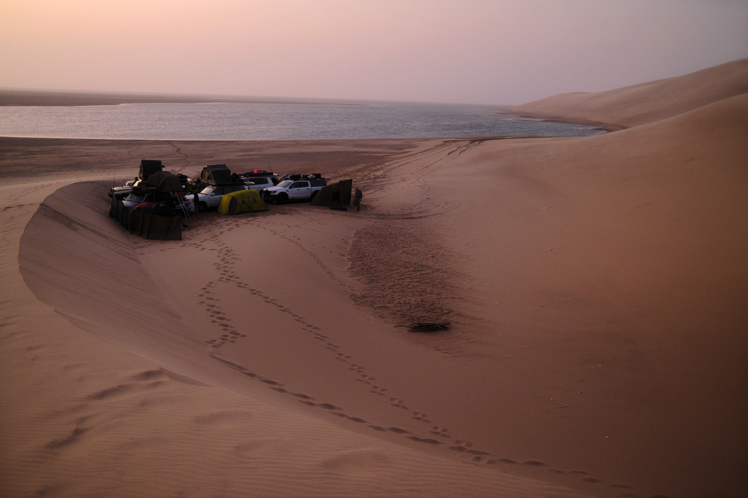 Expedition vehicles among remote Angola dunes at sunset