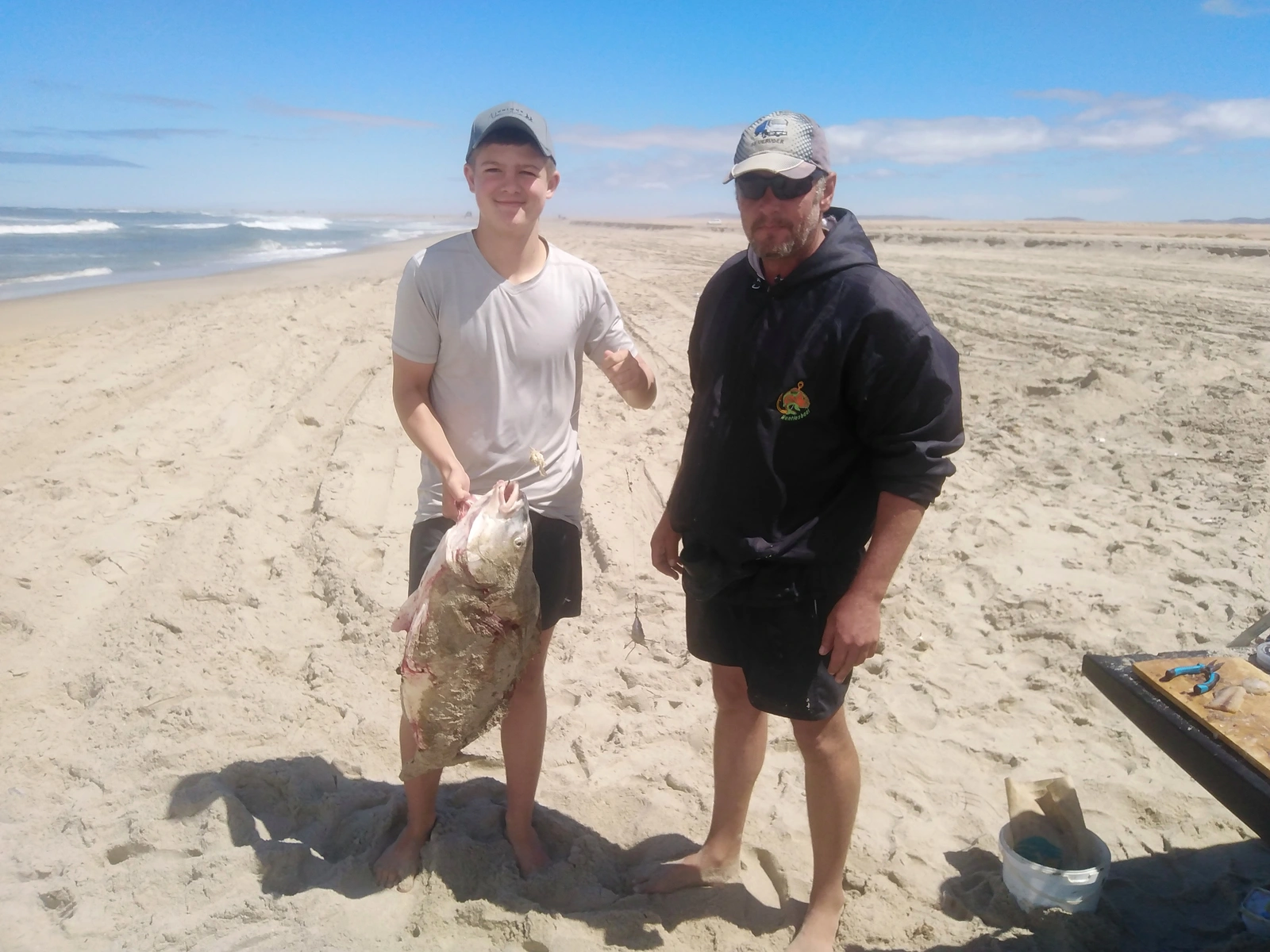 Two anglers standing together on a sunny beach